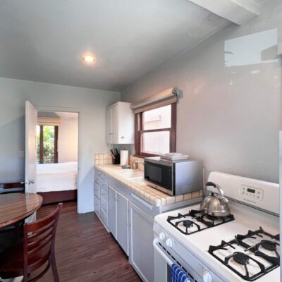 Cozy kitchenette with stove, microwave, and dining area in a small apartment.